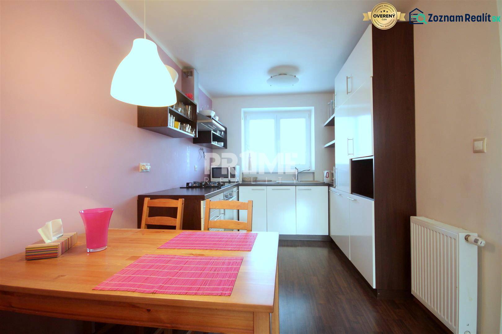 Kétszobás lakás konyhája fa dekoros padlóval és rózsaszín kiegészítőkkel.