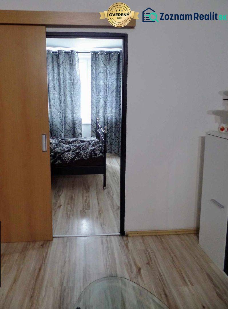 Belső tér fa dekor padlóval, posuvnými dvermi a čiernobielymi závesmi v 3-izbovom byte.