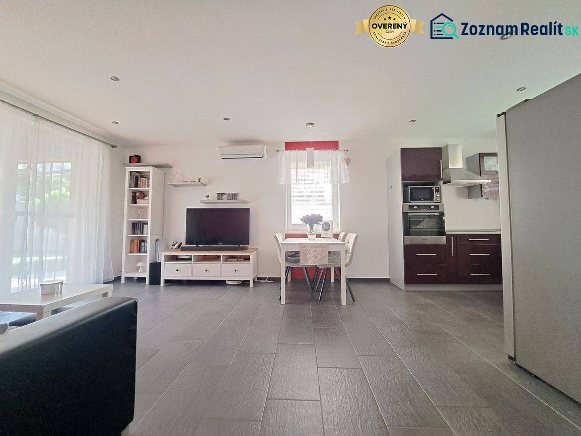 Nappali TV-vel, konyhával és étkezőasztallal, fa dekoros padlóval.