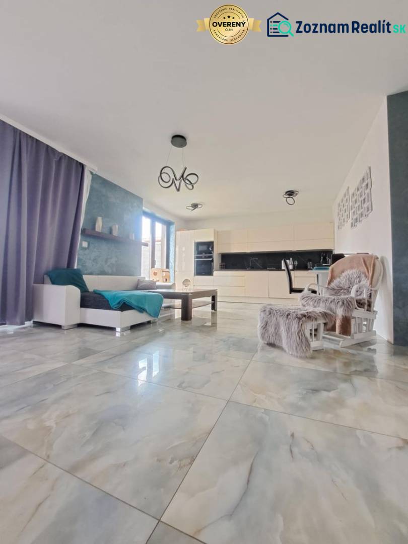 Nappali nagy ablakokkal és világos csempékkel egy családi házban.