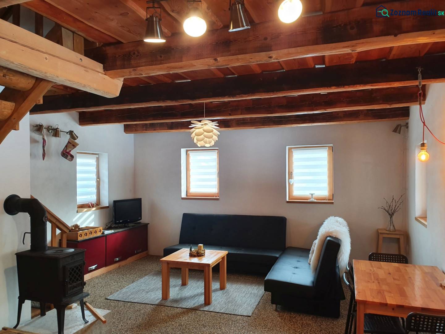 Egy kunyhó belseje cserépkályhával, kanapéval és tömör gerendákból készült fa mennyezettel.