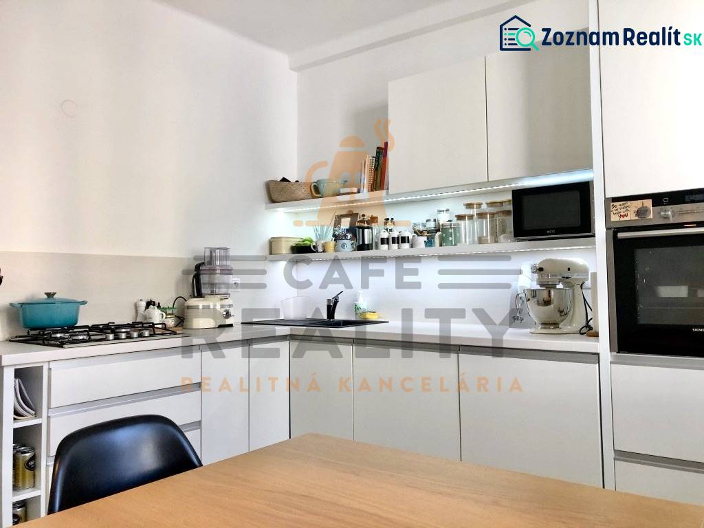 Konyha egy kétszobás lakásban fehér szekrényekkel és beépített készülékekkel.