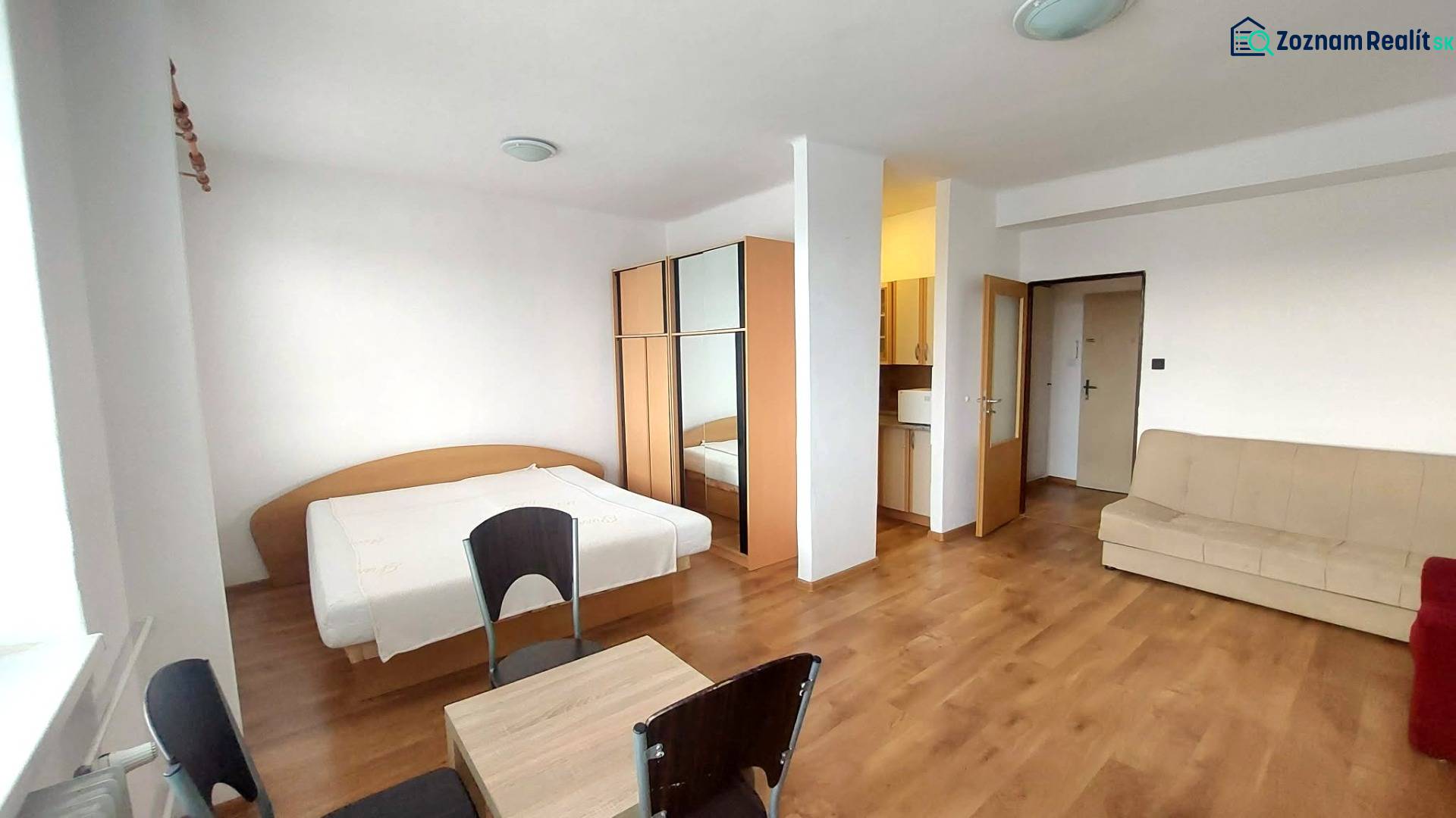 1 szobás lakás fa dekorációs padlóval, ággyal, kanapéval és szekrénnyel.