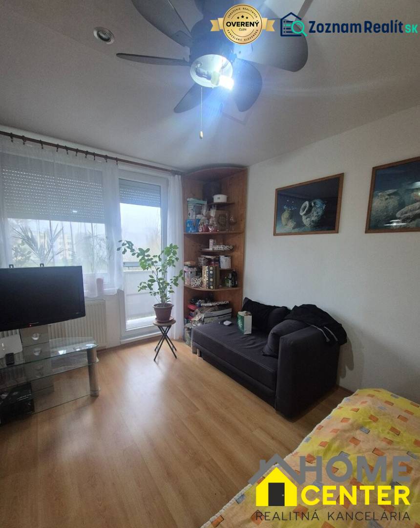 Nappali egy egyszobás lakásban, fa dekorációjú padlóval és kanapéval.