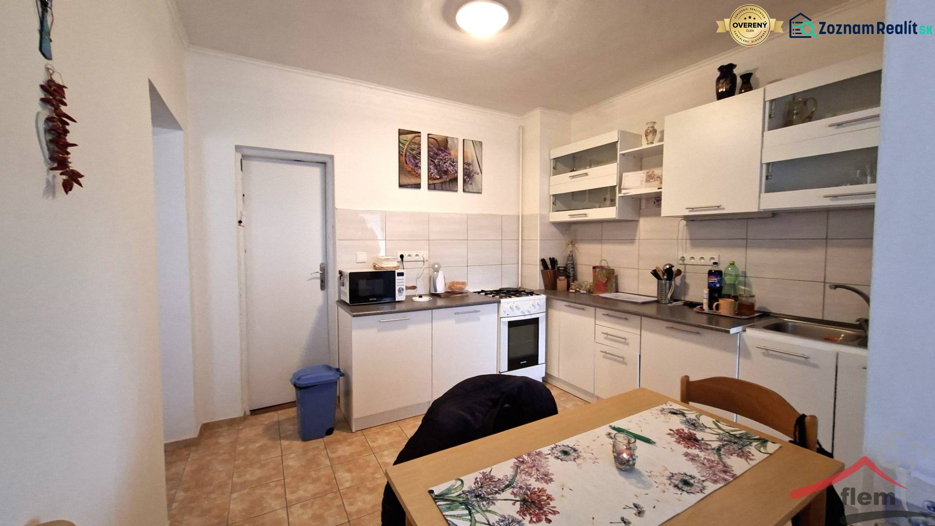 Konyha családi házban fehér bútorokkal, tűzhellyel és étkezőasztallal.