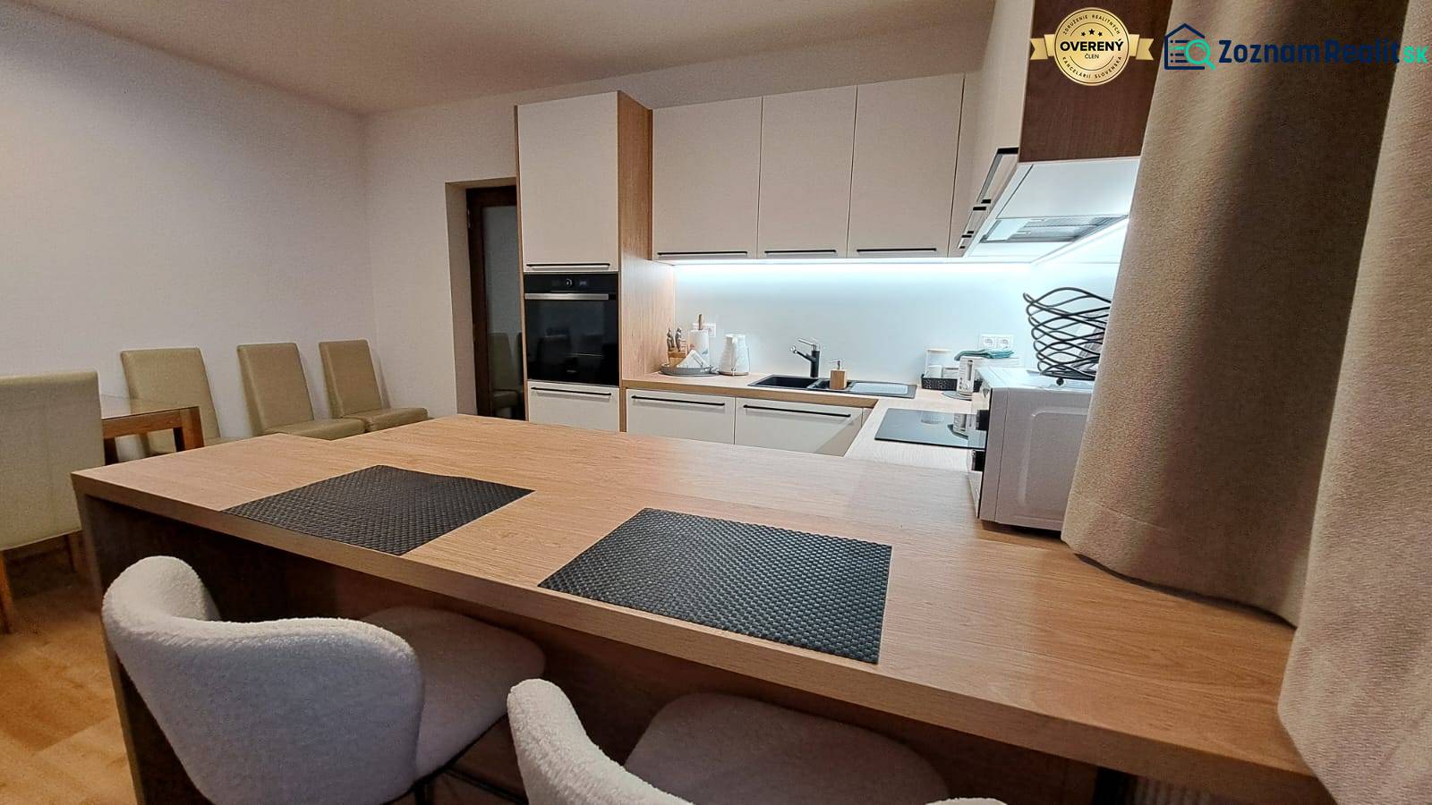 Konyha egy kétszobás lakásban beépített készülékekkel és fa hatású padlóval.