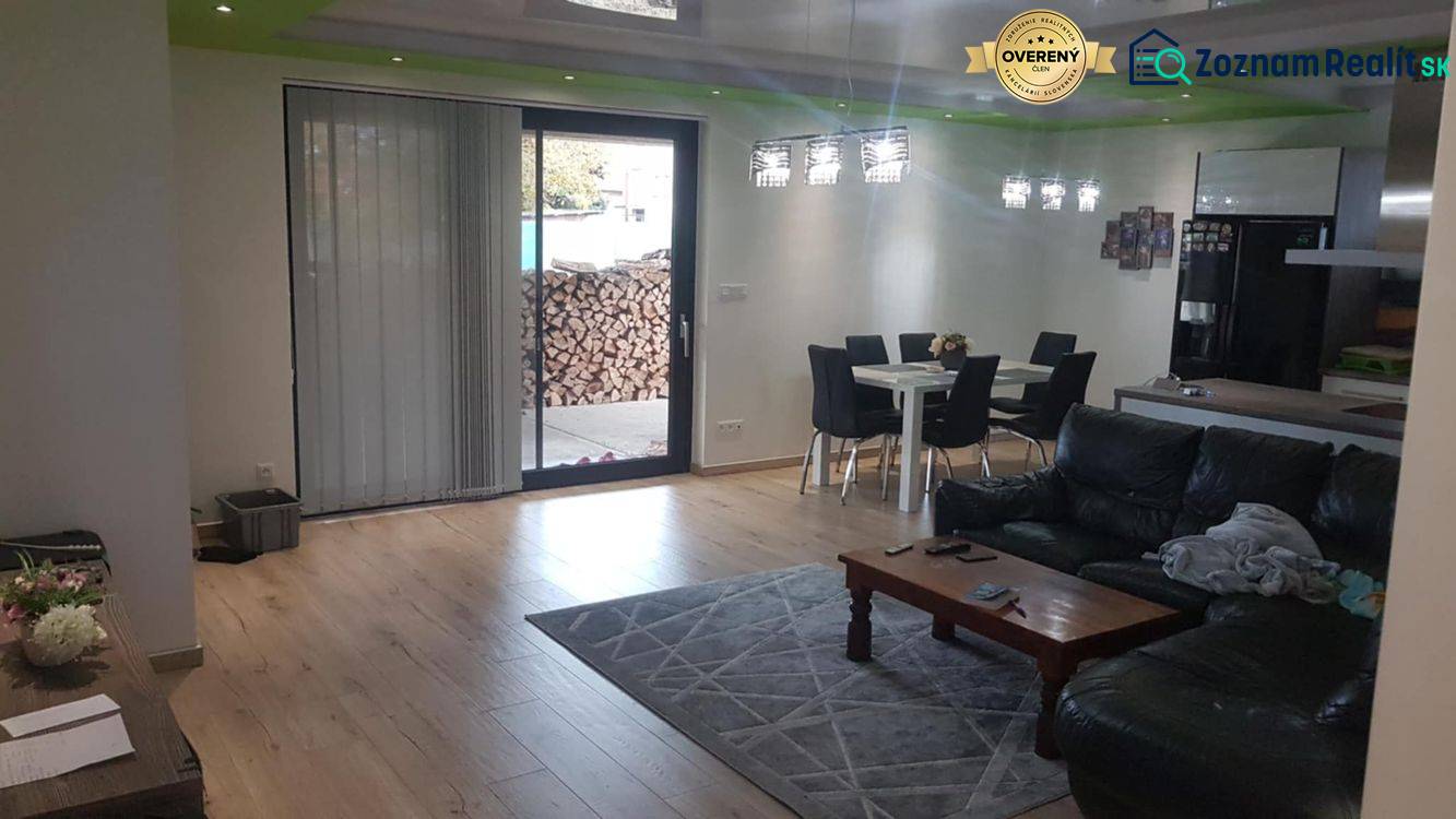 Nappali egy családi házban, fa mintázatú padlóval, kanapéval és étkezőasztallal.