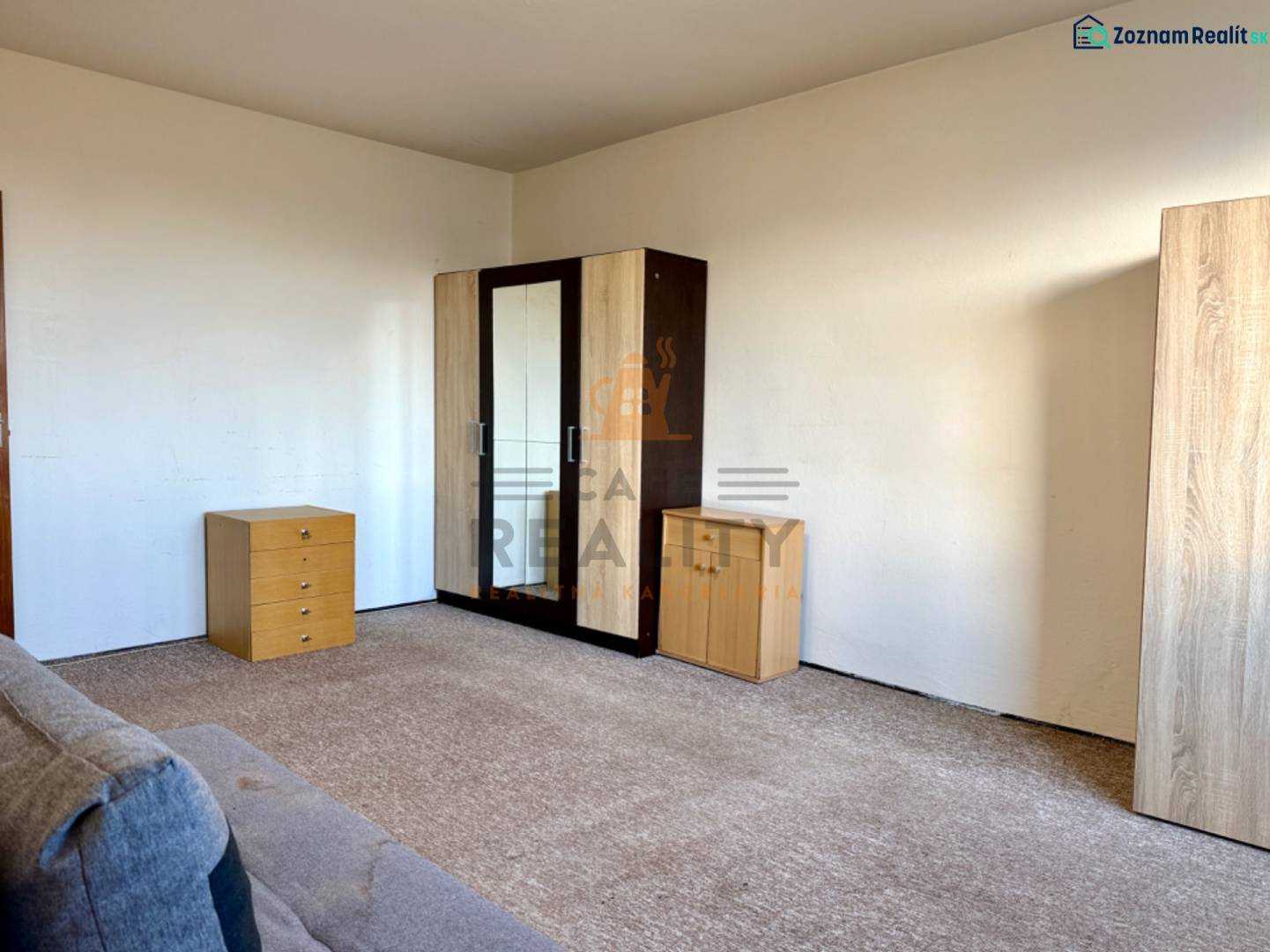 Egy szoba egy egyszobás lakásban komóddal, szekrénnyel és szőnyeggel a padlón.