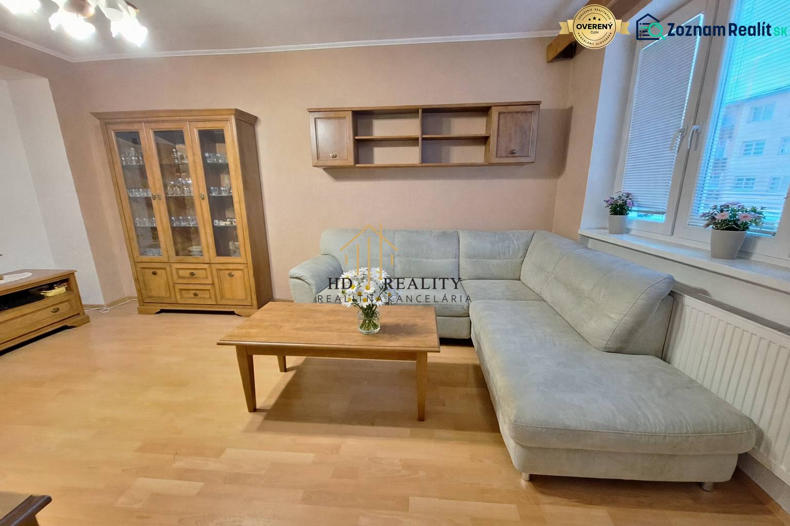 Nappali egy kétszobás lakásban sarokkanapéval, a fa dekoráció kiegészíti a belső teret.