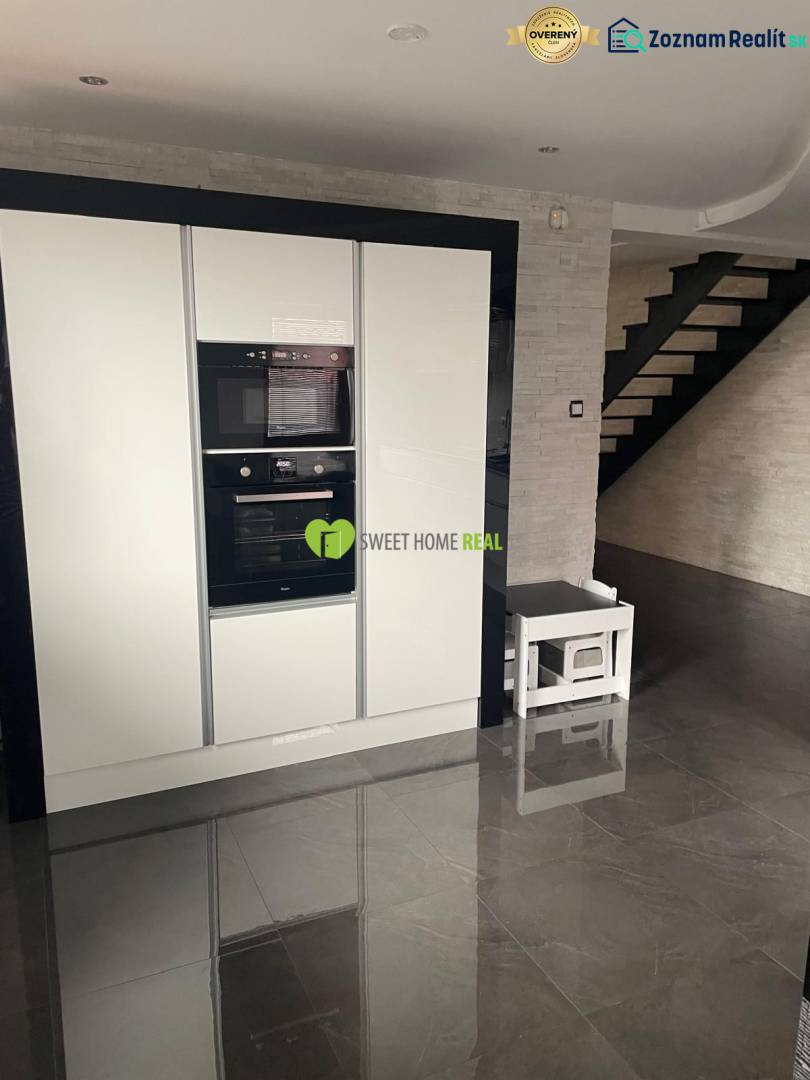 Konyha egy családi házban fényes fekete padlóval és fehér készülékekkel.