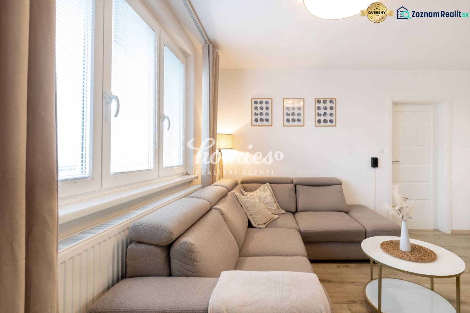 Nappali egy kétszobás lakásban kényelmes kanapéval és faldekorációkkal.