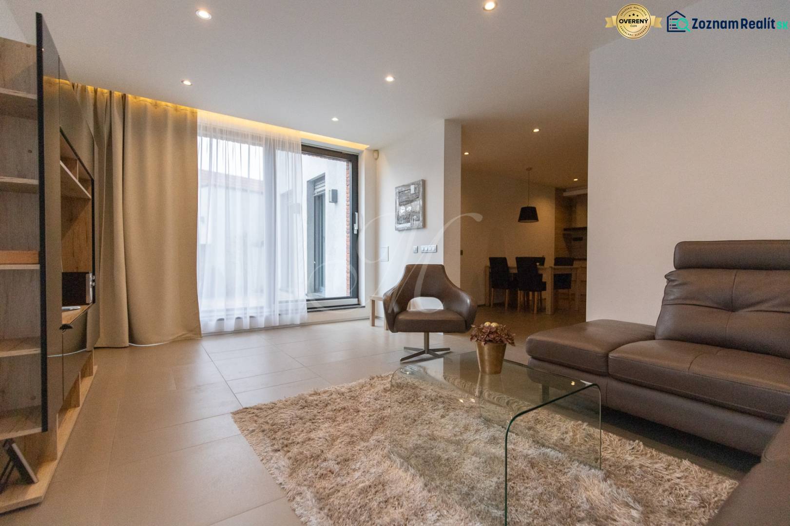 Nappali egy kétszobás lakásban kényelmes kanapéval, fotellel és üvegasztallal.