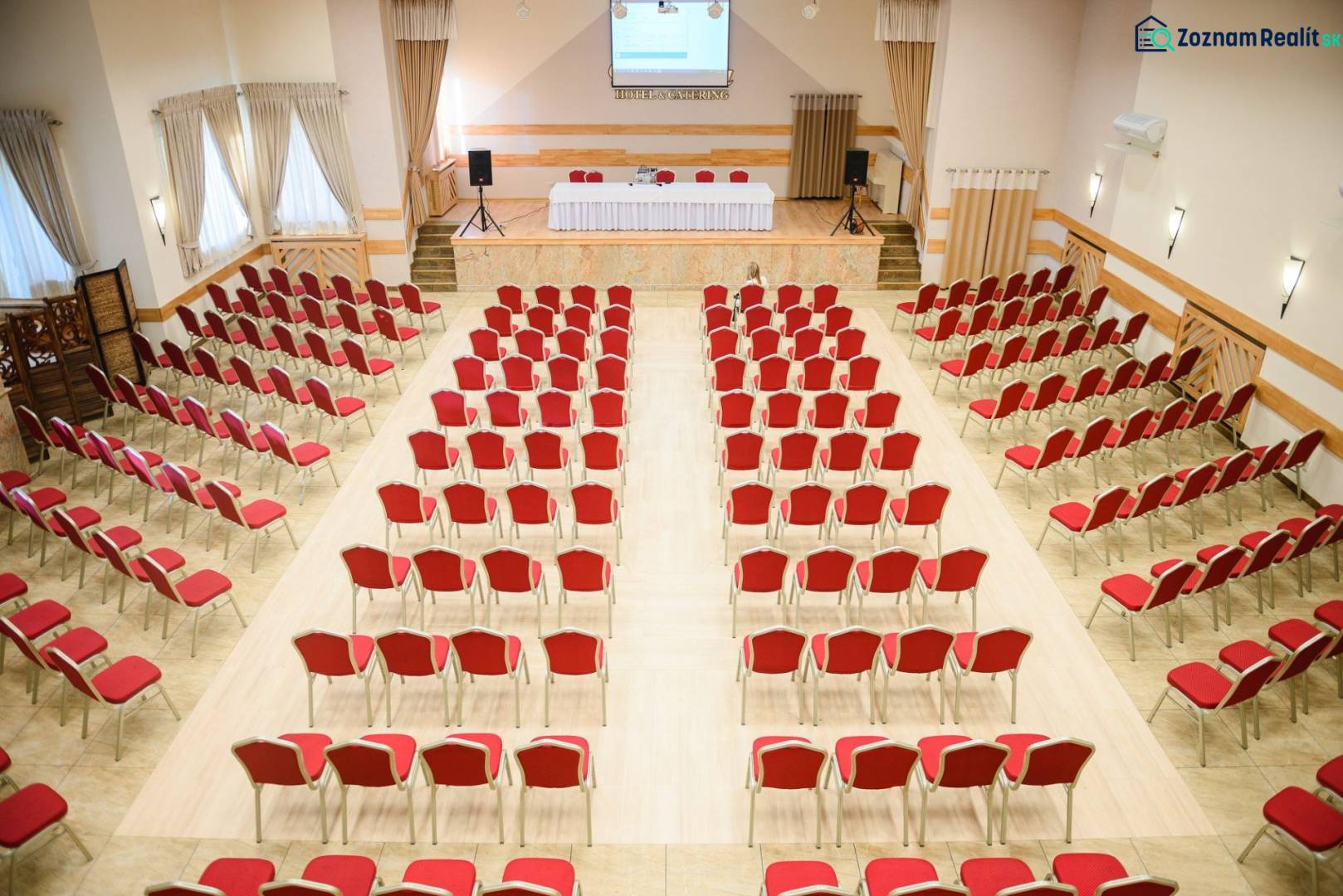 Konferenciaterem piros székekkel és fa mintázatú padlóval szállodákban és panziókban.