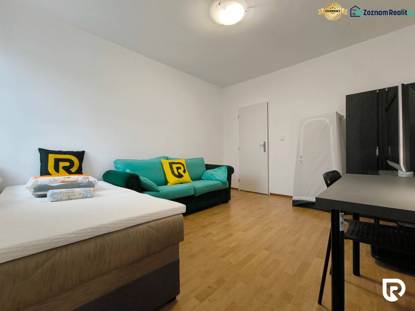 Egy családi ház szobája ággyal, kanapéval és íróasztallal, fa dekorációjú padlóval.