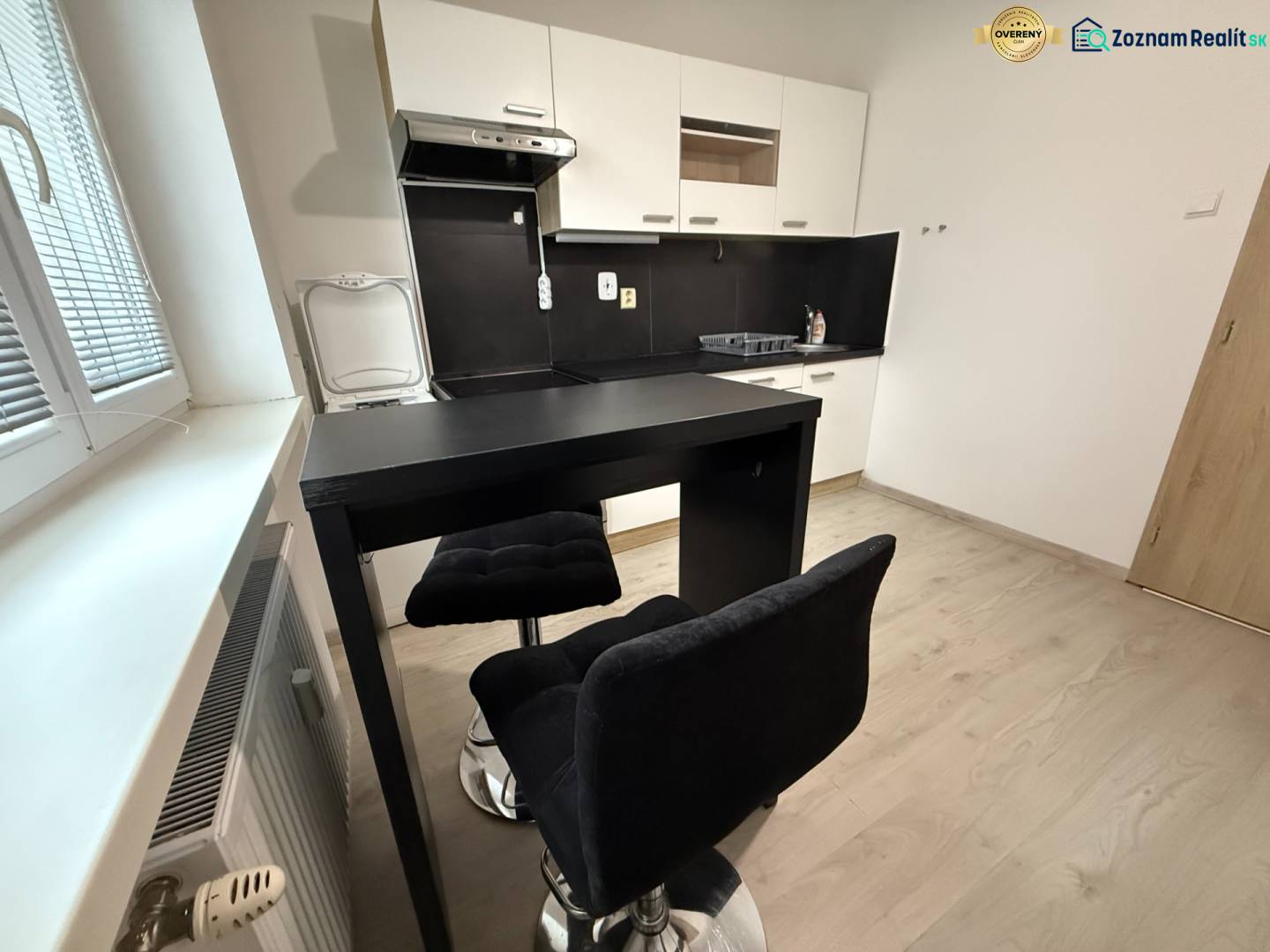 Konyha ülőhellyel és fa dekoros padlóval egy egyszobás lakásban.