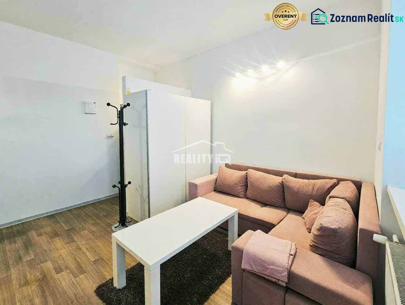 Garzonlakás sarokkanapéval, fehér asztallal és fa dekorációjú padlóval.