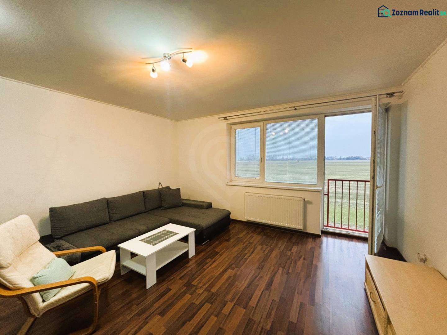 Nappali egy kétszobás lakásban, fa dekor padlóval és kanapéval.