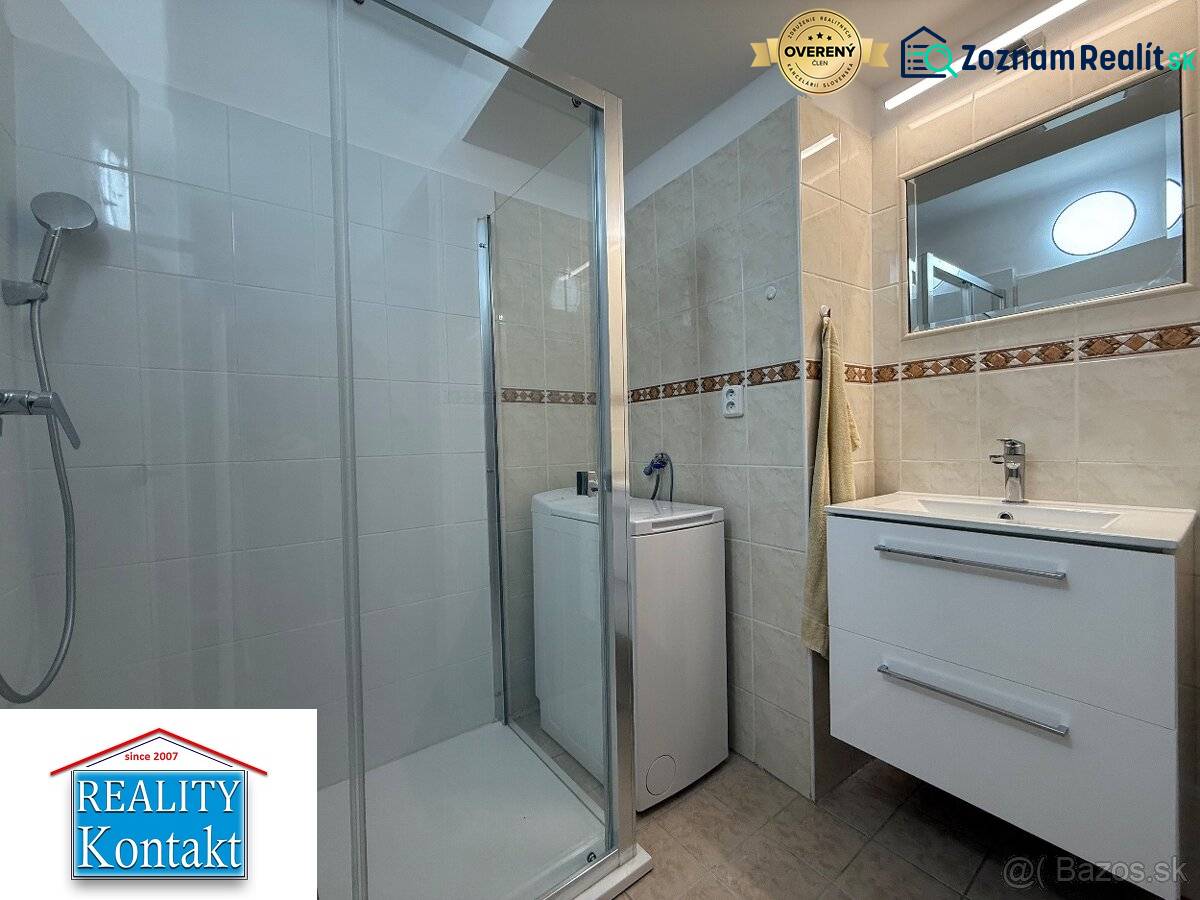 Fürdőszoba egy kétszobás lakásban mosdóval, zuhanyzóval és mosógéppel.