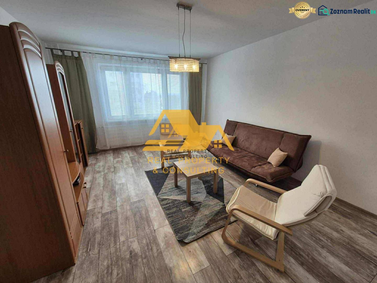 Nappali egy háromszobás lakásban kanapéval, fotellel és fa dekorációjú padlóval.