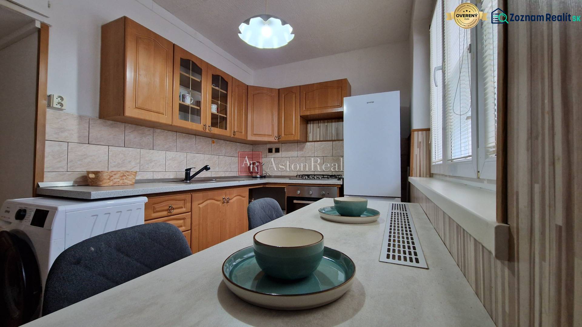 Konyha fa szekrényekkel és étkezőasztallal egy kétszobás lakásban.