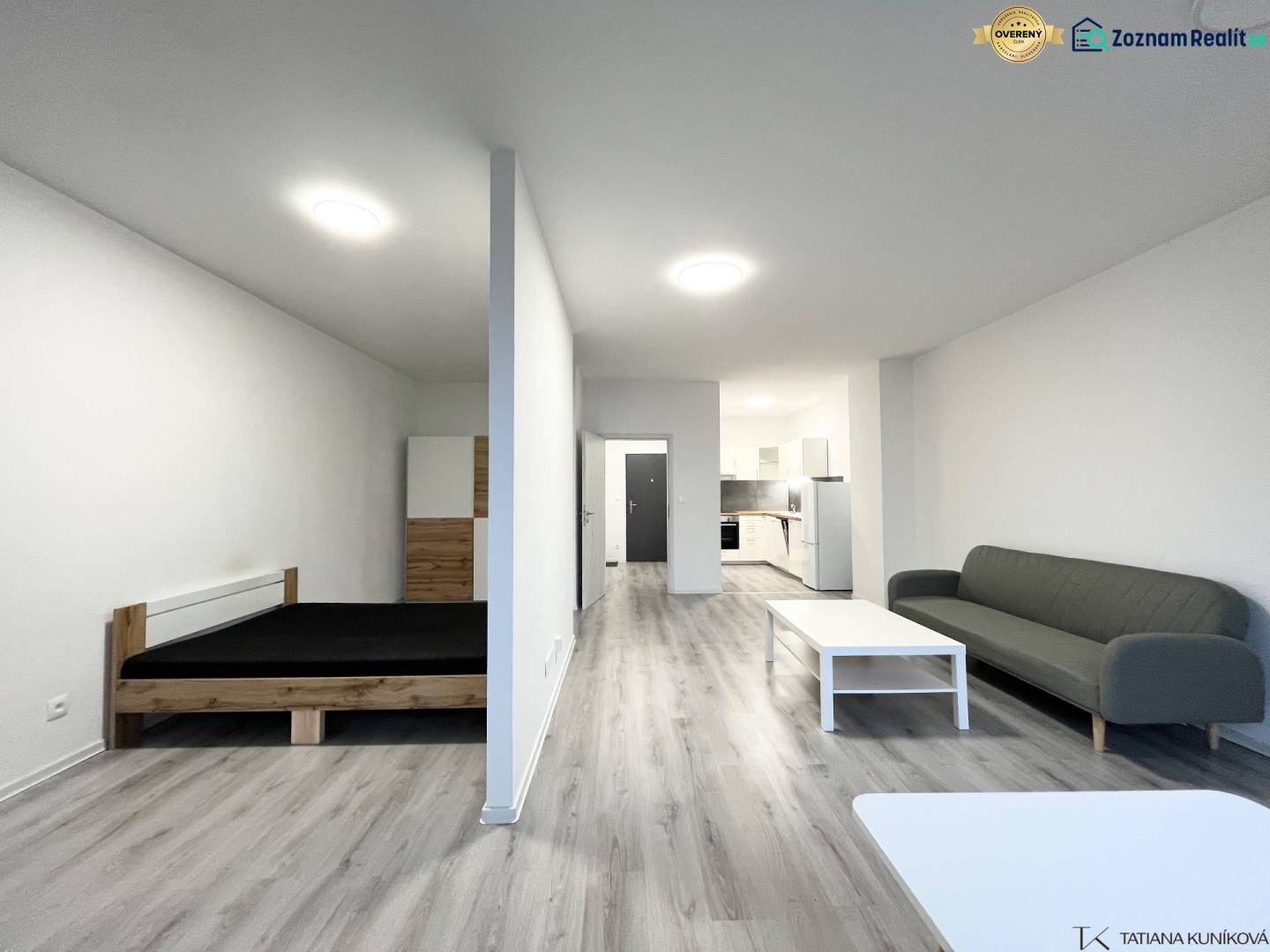 1 szobás lakás belső tere fa dekorációjú padlóval, ággyal és kanapéval.