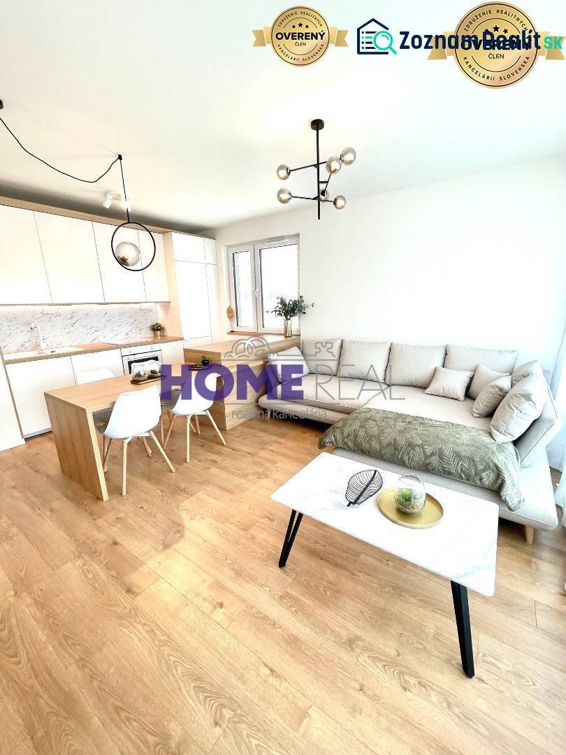 Nappali konyhával egy háromszobás lakásban, világos kanapé, fa dekoros padló.