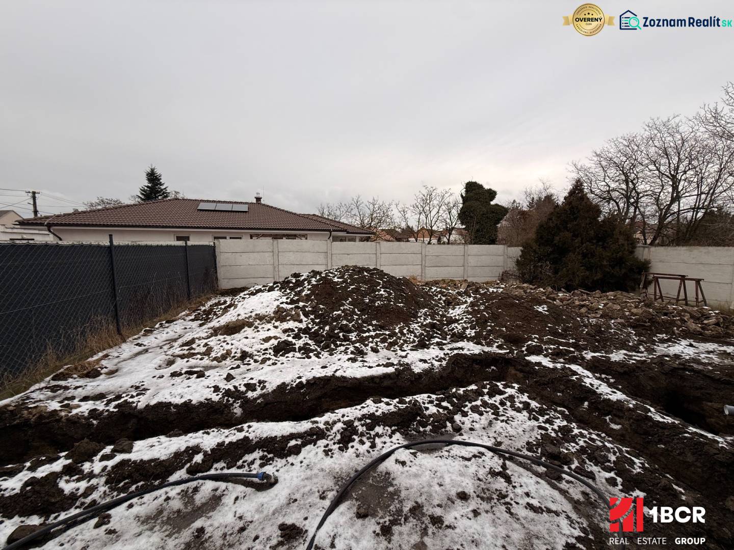 Családi ház építési területe Szencen téli időszakban kerítéssel és hóval.