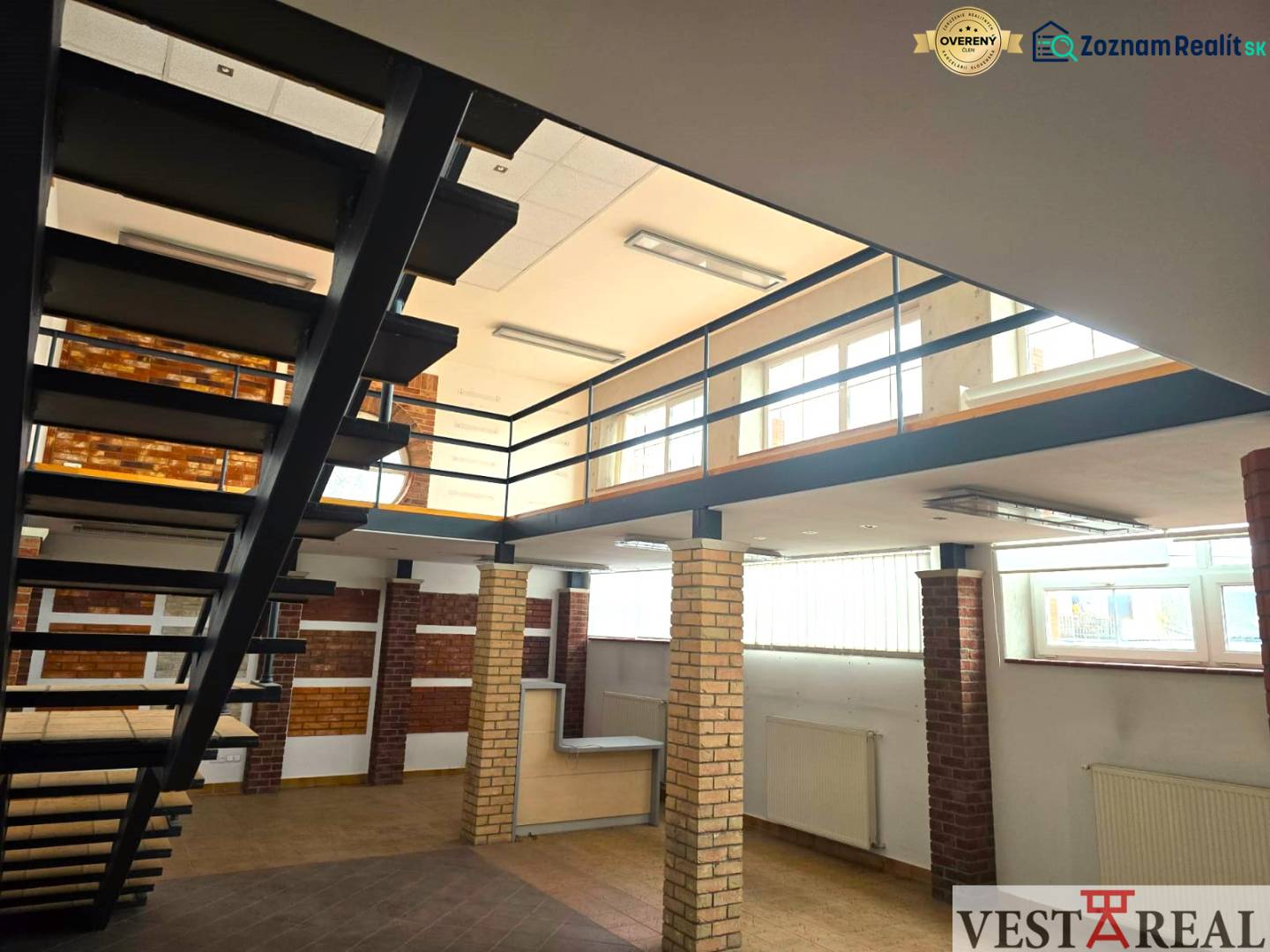 Beltéri üzlethelyiségek fa mintázatú padlóval és fém lépcsővel.