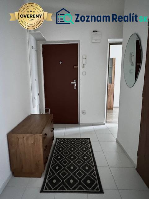 Folyosó egy kétszobás lakásban fehér csempével és fa berendezéssel.