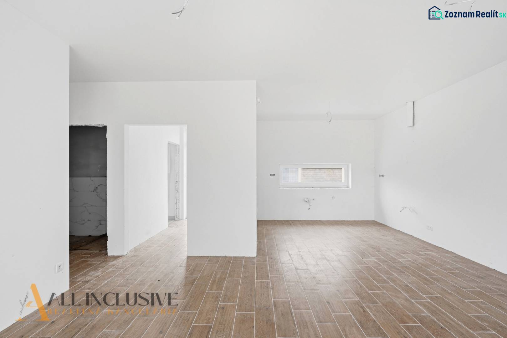 Családi ház belső tere fa dekorációjú padlóval és fehér falakkal.