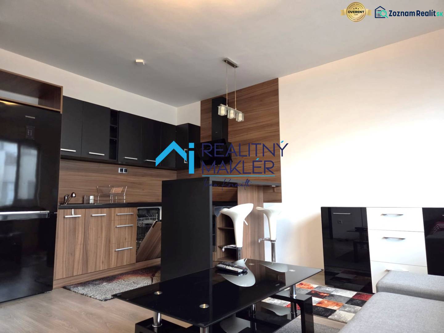 Konyha egy egyszobás lakásban fekete szekrényekkel, fa dekor padlóval.