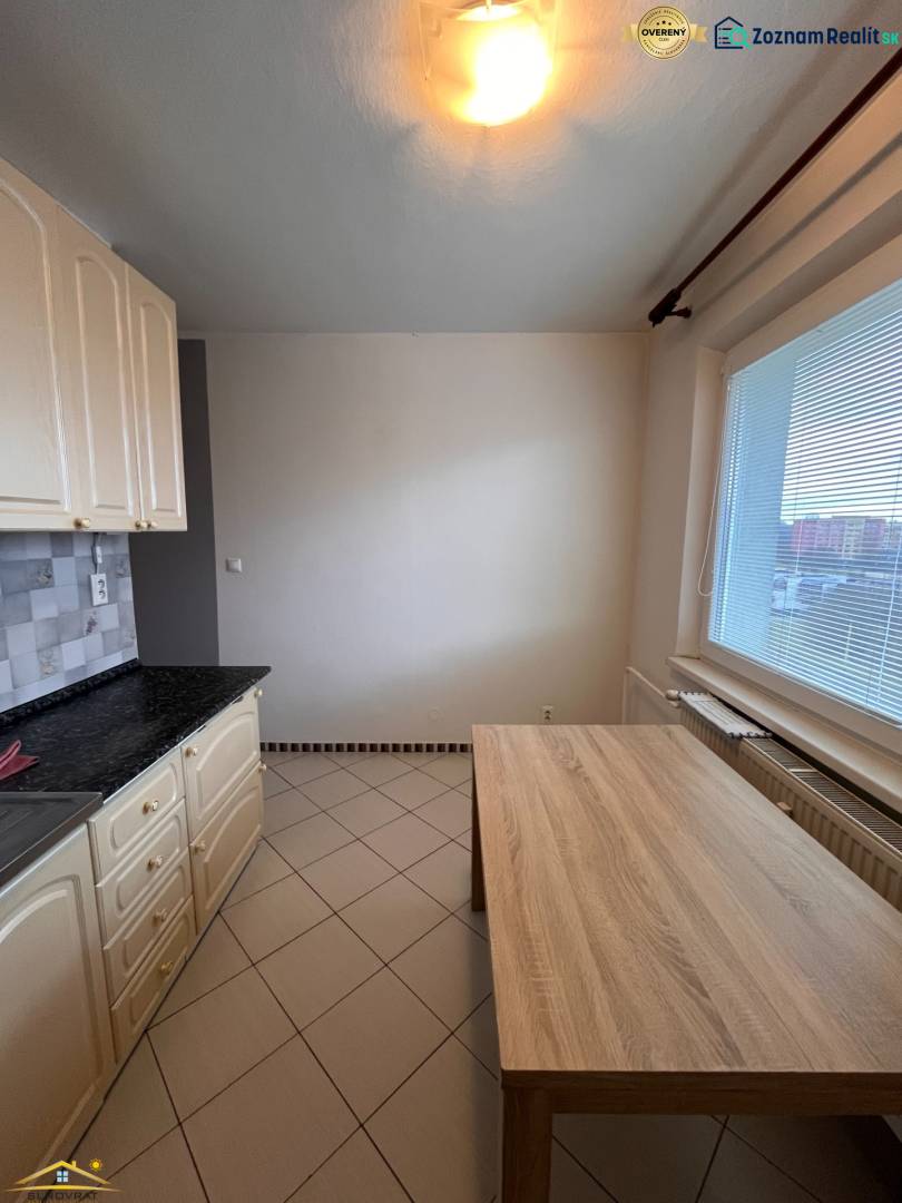 Konyha egy kétszobás lakásban kerámia padlóval és étkezőasztallal.