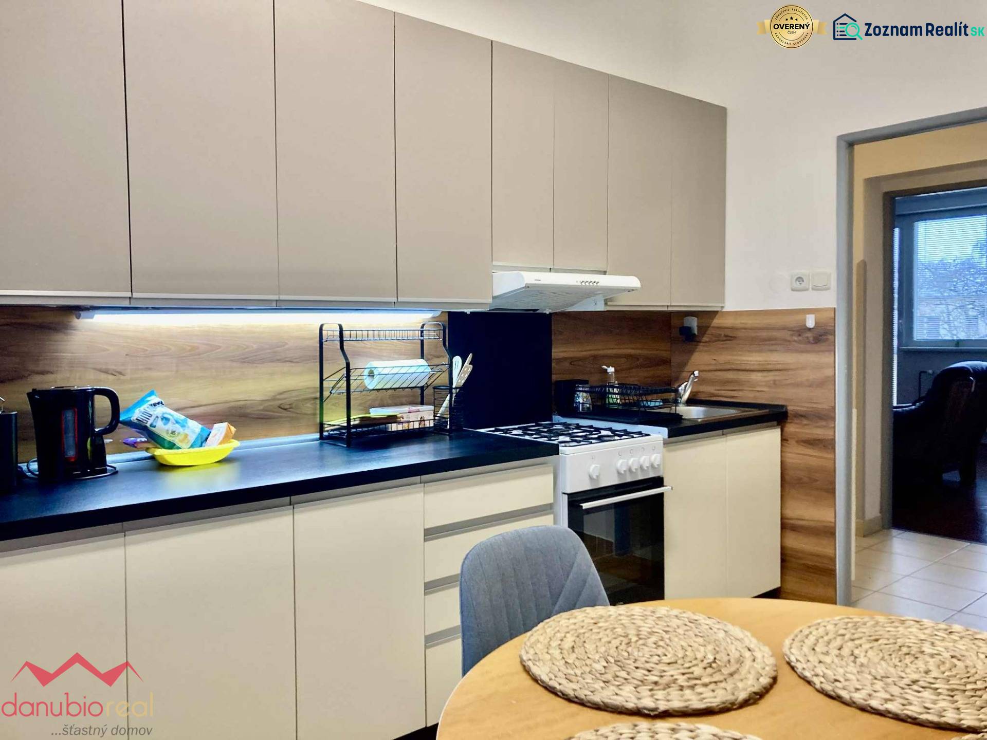 Konyha egy háromszobás lakásban, fa dekorációjú padlóval és modern felszereléssel.