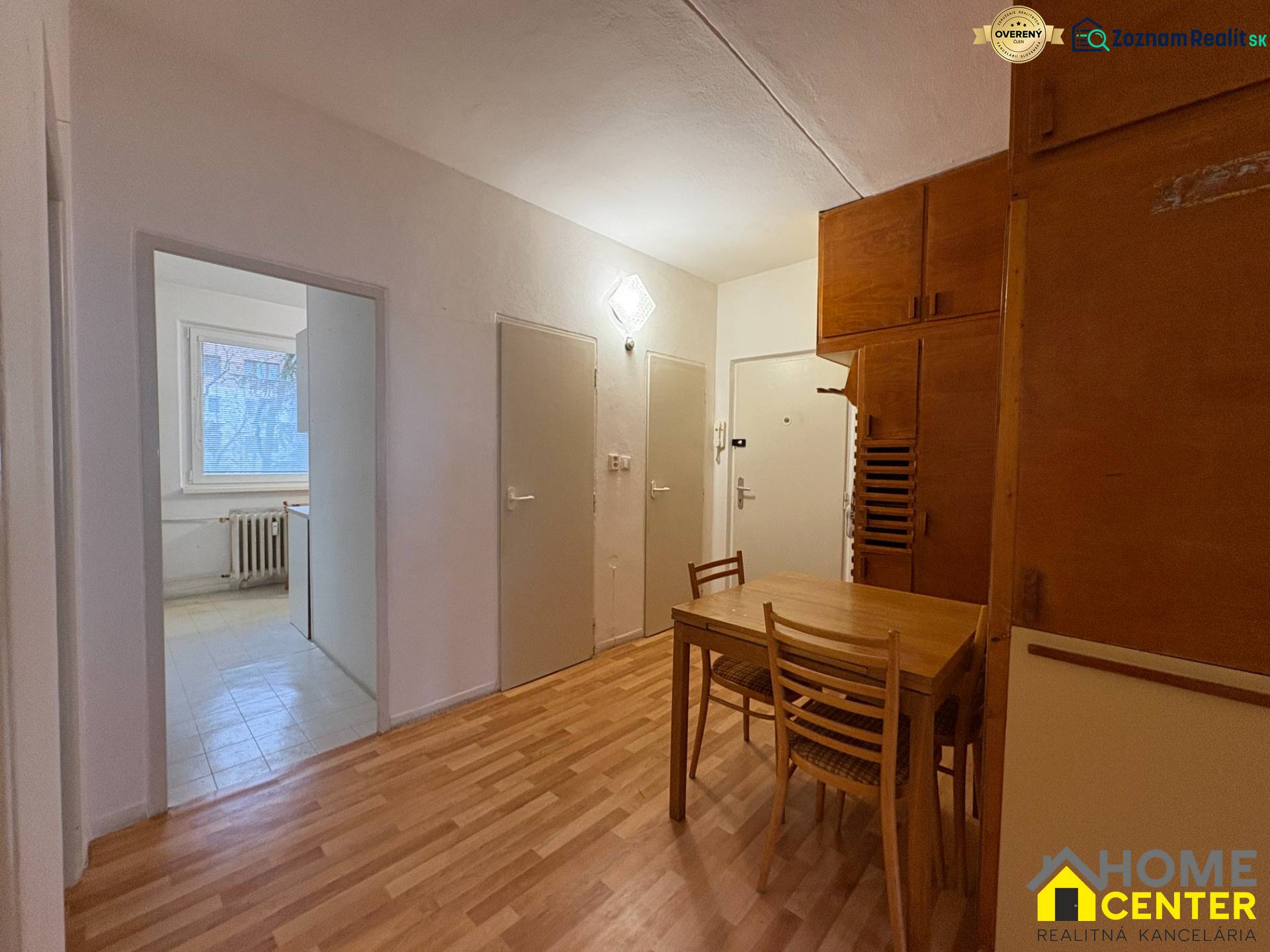 3 szobás lakás belső tere fa mintázatú padlóval, étkező sarok asztallal és székekkel.