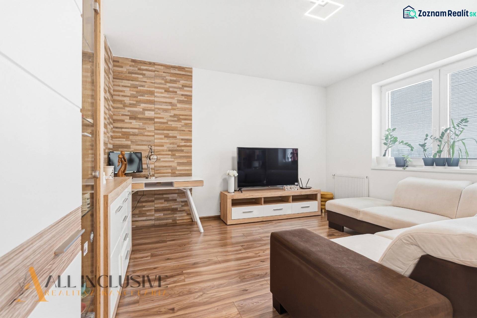 Nappali fa hatású padlóval, TV-vel és krémszínű kanapéval egy kétszobás lakásban.