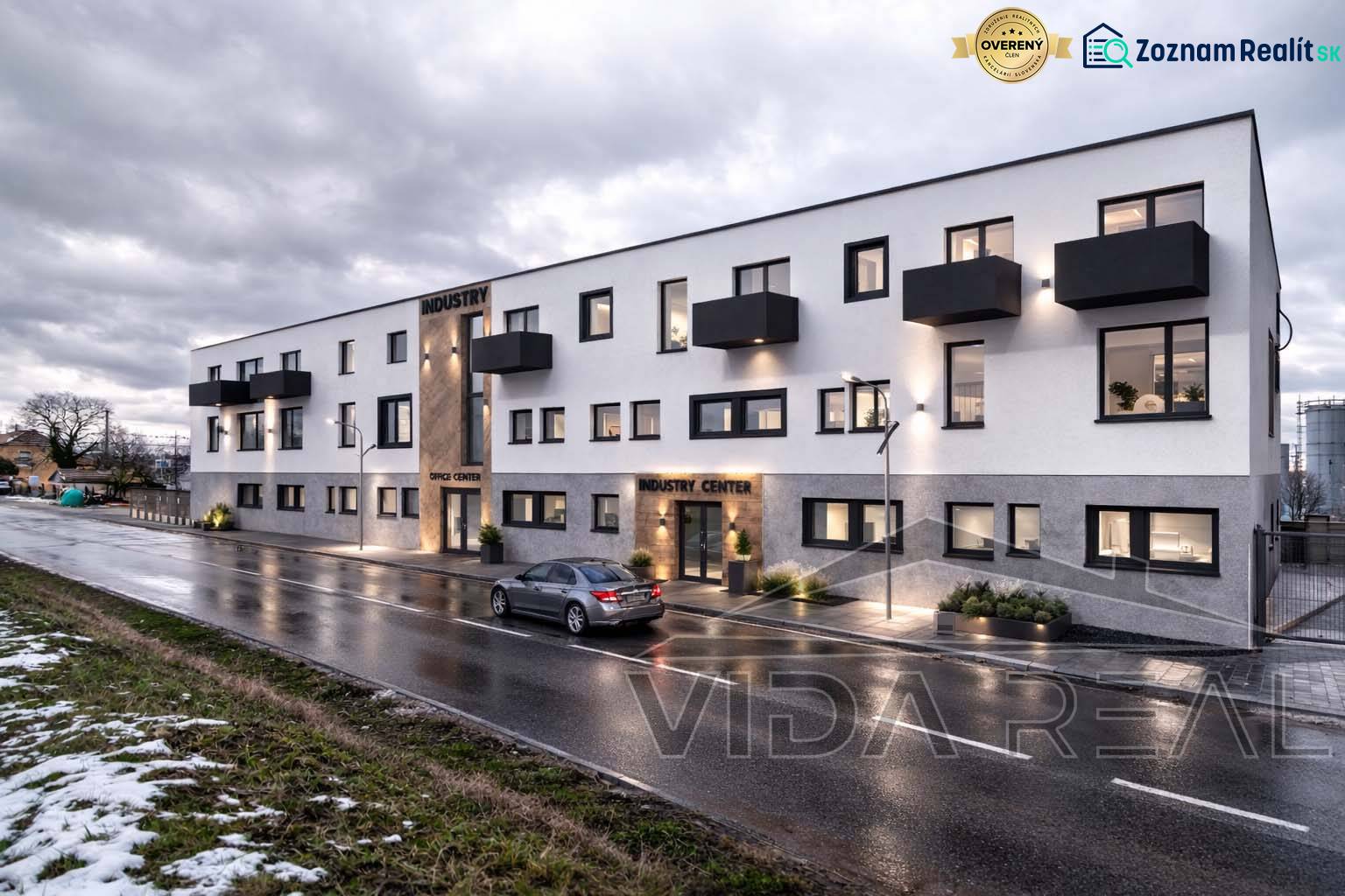 Épület a Šenkvicei Nádražná utcában, raktárak és csarnokok, esti világítással.