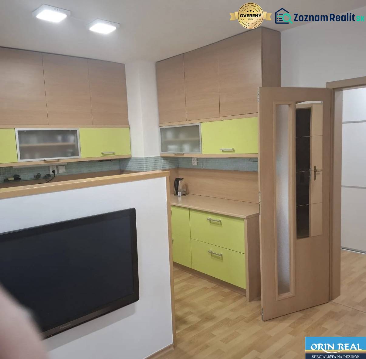 Konyha egy kétszobás lakásban, fa dekor padlóval és színes szekrényekkel.