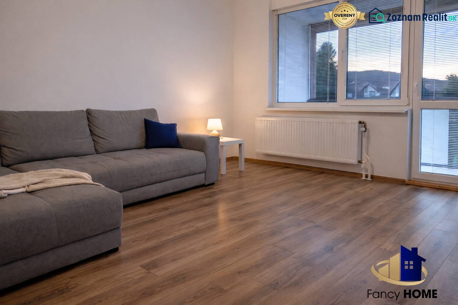 Nappali egy háromszobás lakásban kanapéval és fa dekorációjú padlóval.