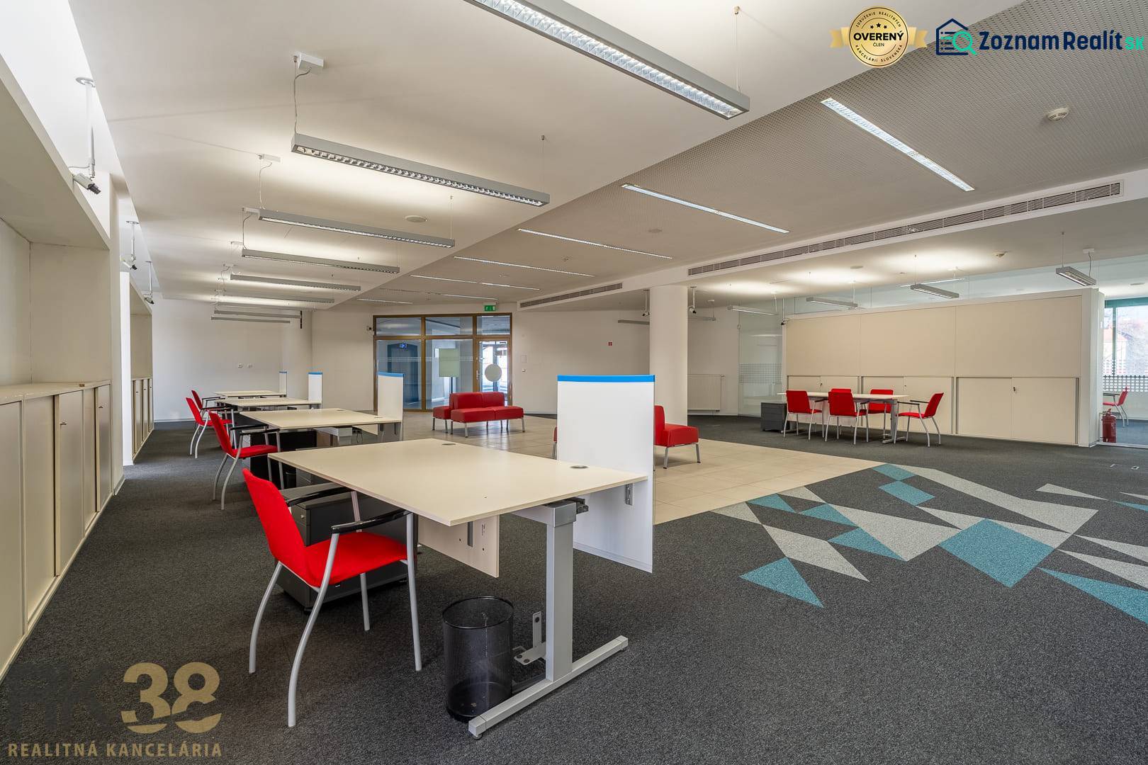 Irodák belső tere piros székekkel és szőnyegmintás padlóval.