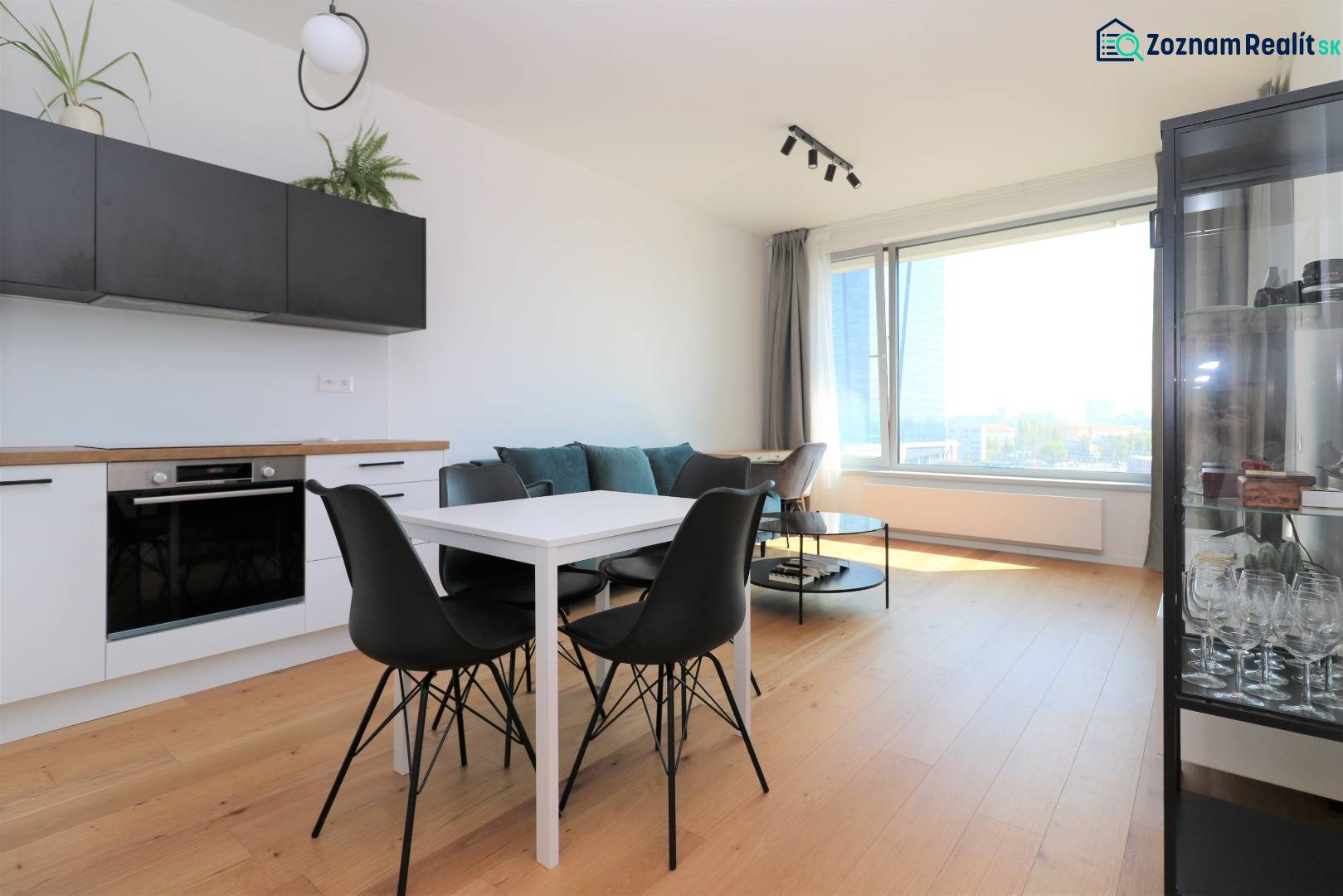 Konyha és étkezőasztal fekete székekkel egy kétszobás lakásban, fa dekorációjú padlóval.