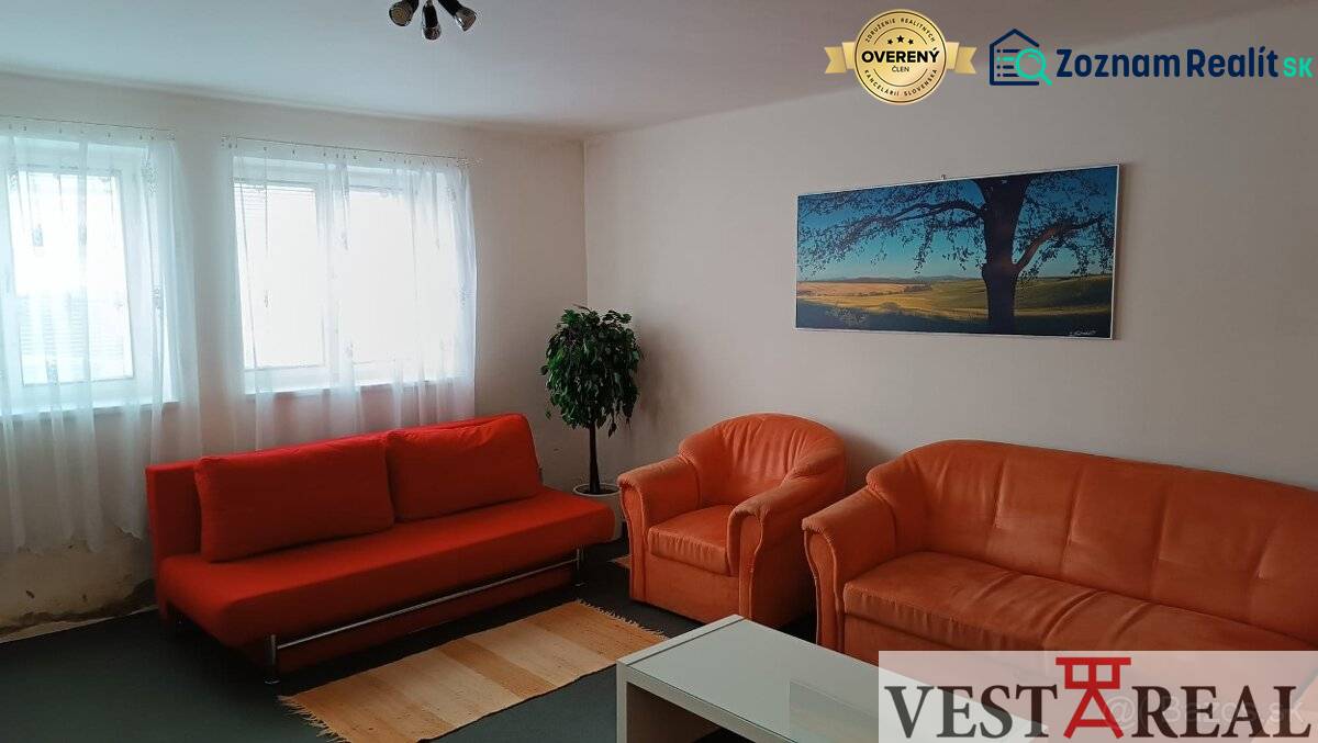 Nappali egy családi házban narancssárga kanapéval, fotelekkel és tájképpel.