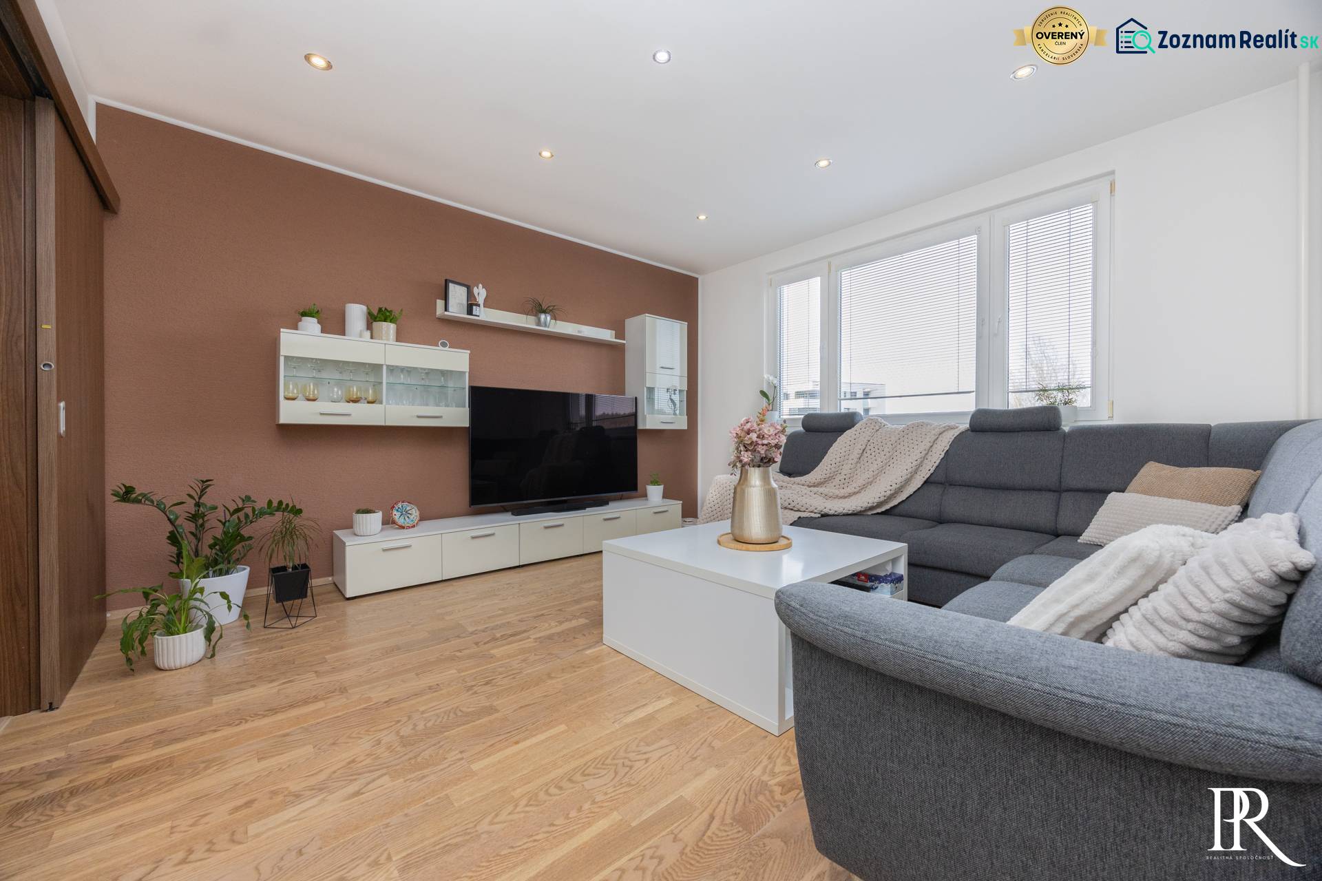 Nappali szürke kanapéval, fehér bútorokkal, fa mintázatú padlóval, 4 szobás lakás.