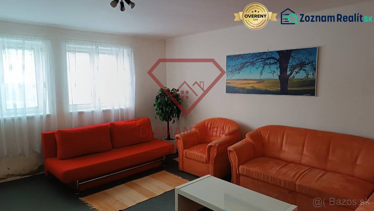 Nappali egy családi házban narancssárga kanapéval, fotelekkel és tájképpel.