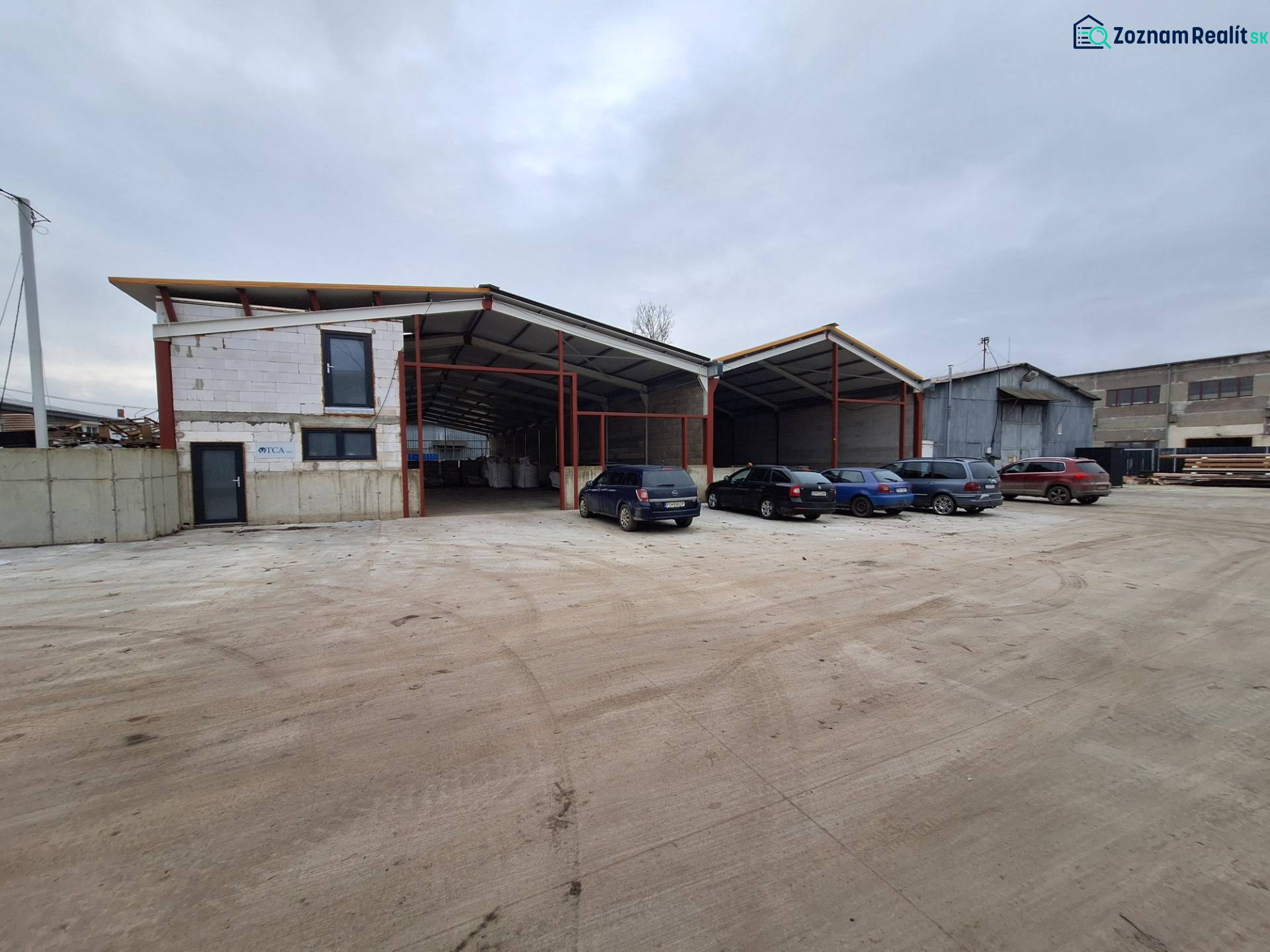 Raktár- és csarnokterület a Strojnícka utcában, Eperjesen, parkolóval és autókkal.