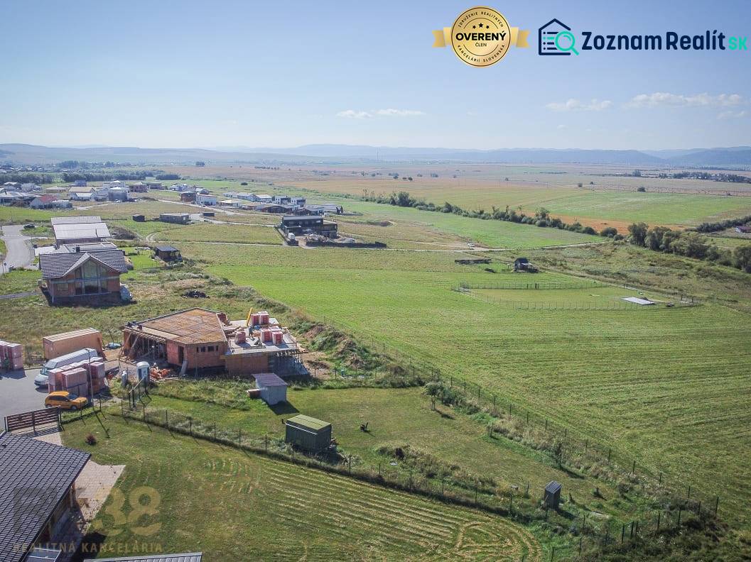Telkek - lakóhely Mlynicában; épülő házak és kiterjedt mezők a napos égbolt alatt.