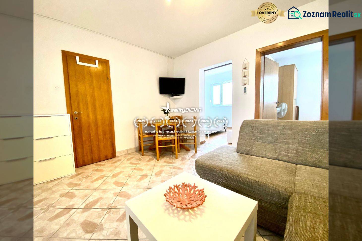 Nappali egy családi házban kanapéval, asztallal és falra szerelt televízióval.