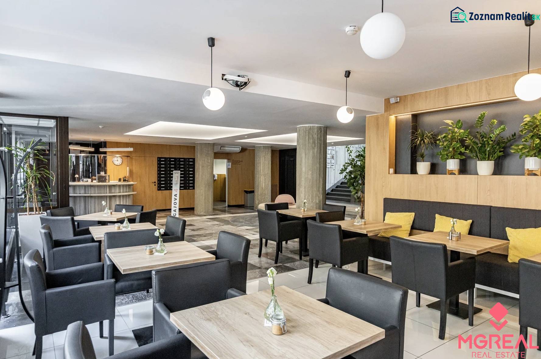 Irodák fa dekor padlóval, asztalokkal, fekete székekkel és növényekkel Pozsonyban.
