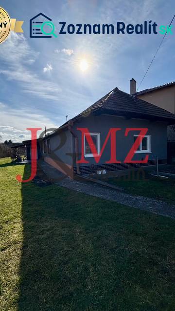 Családi ház Mýtne Ludanban, kerttel körülvéve, kék égbolttal és nappal.