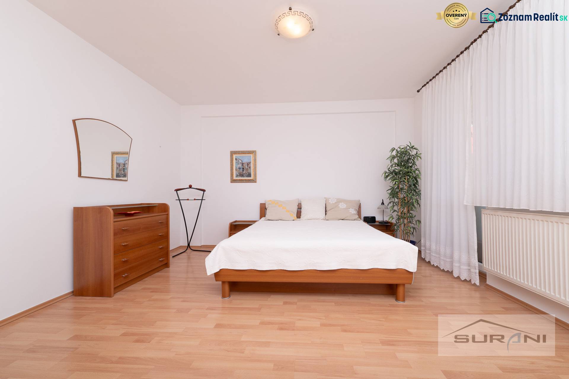 Hálószoba ággyal, komóddal és fa dekorációjú padlóval egy háromszobás lakásban.