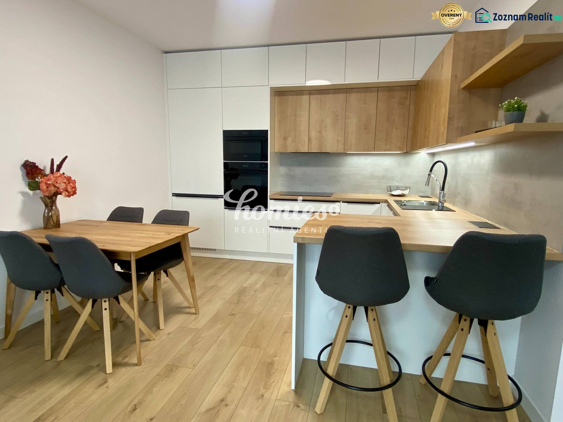 Konyha egy kétszobás lakásban, fa dekoros padlóval, étkezőasztallal és bárpulttal.